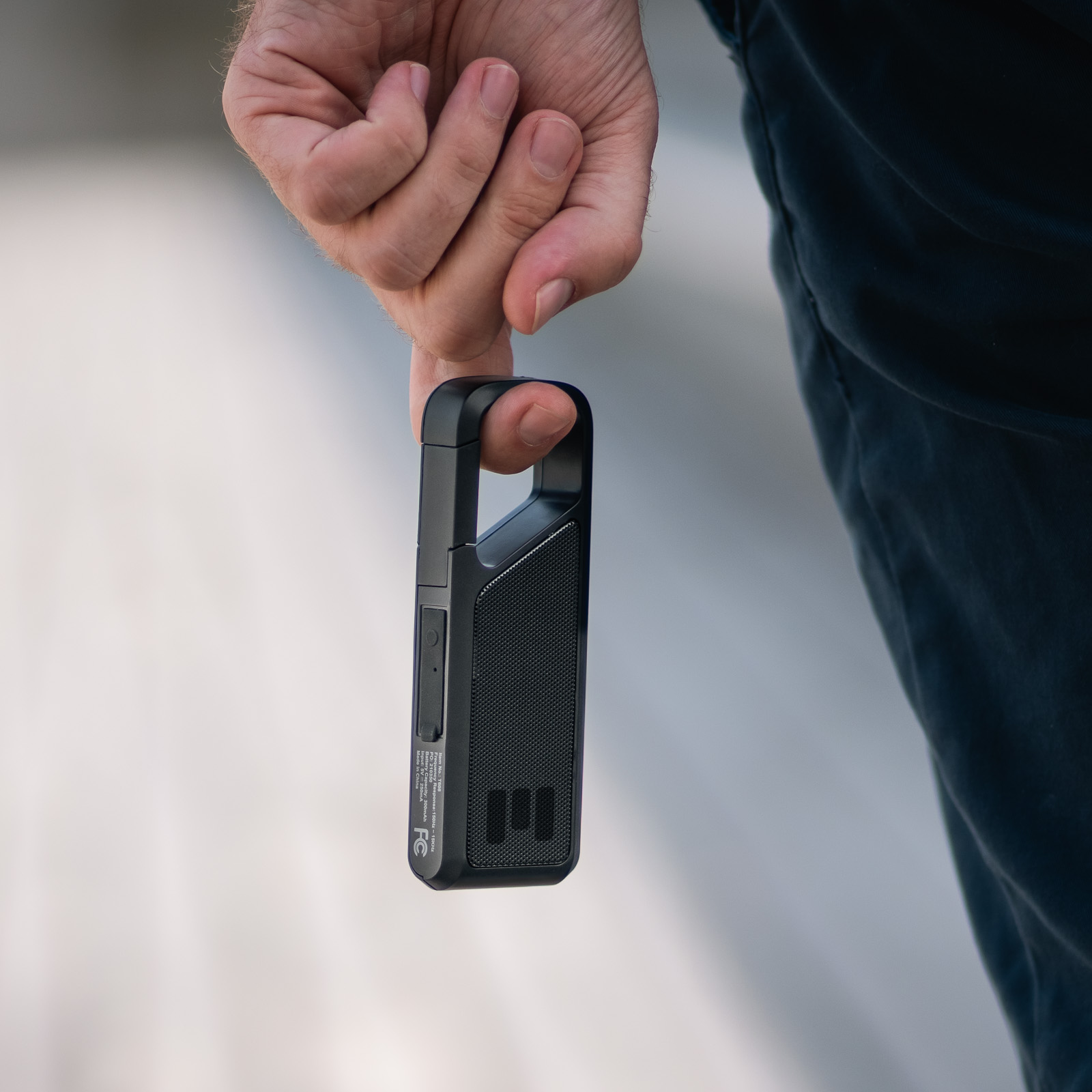 MiniGO draadloze clip-speaker in de hand, met karabijnhaak en spatwaterdichte behuizing